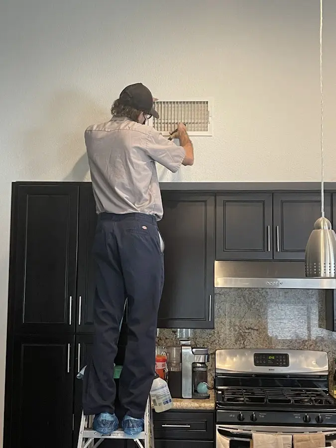 Technician inspecting an air vent during HVAC service in Liberal